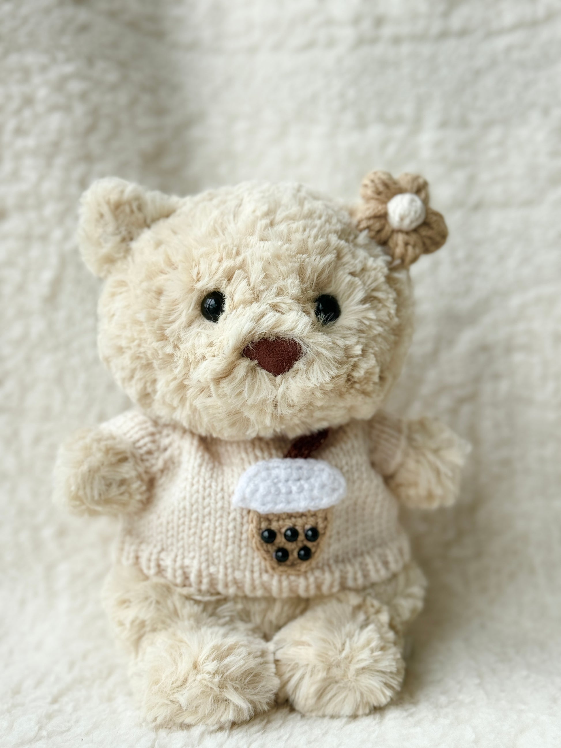 Handmade boba tea knit sweater and crochet flower clip on Jellycat Bartholomew Bear Junior, cream oat tones, front view