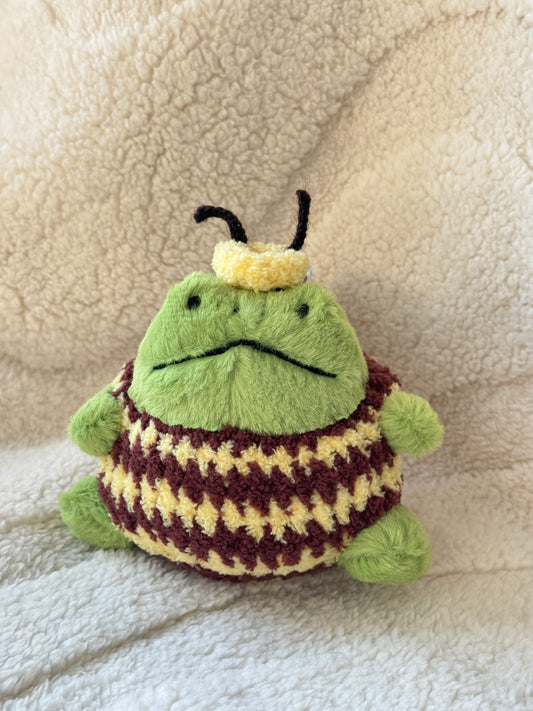 Jellycat Ricky Rain Frog wearing a handmade bumble bee outfit with yellow and brown stripes, tiny wings, and bee antennae headband.