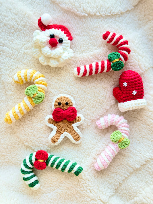 Handmade crochet Christmas miniatures including Santa, gingerbread and candy cane ornaments on a fluffy cream background