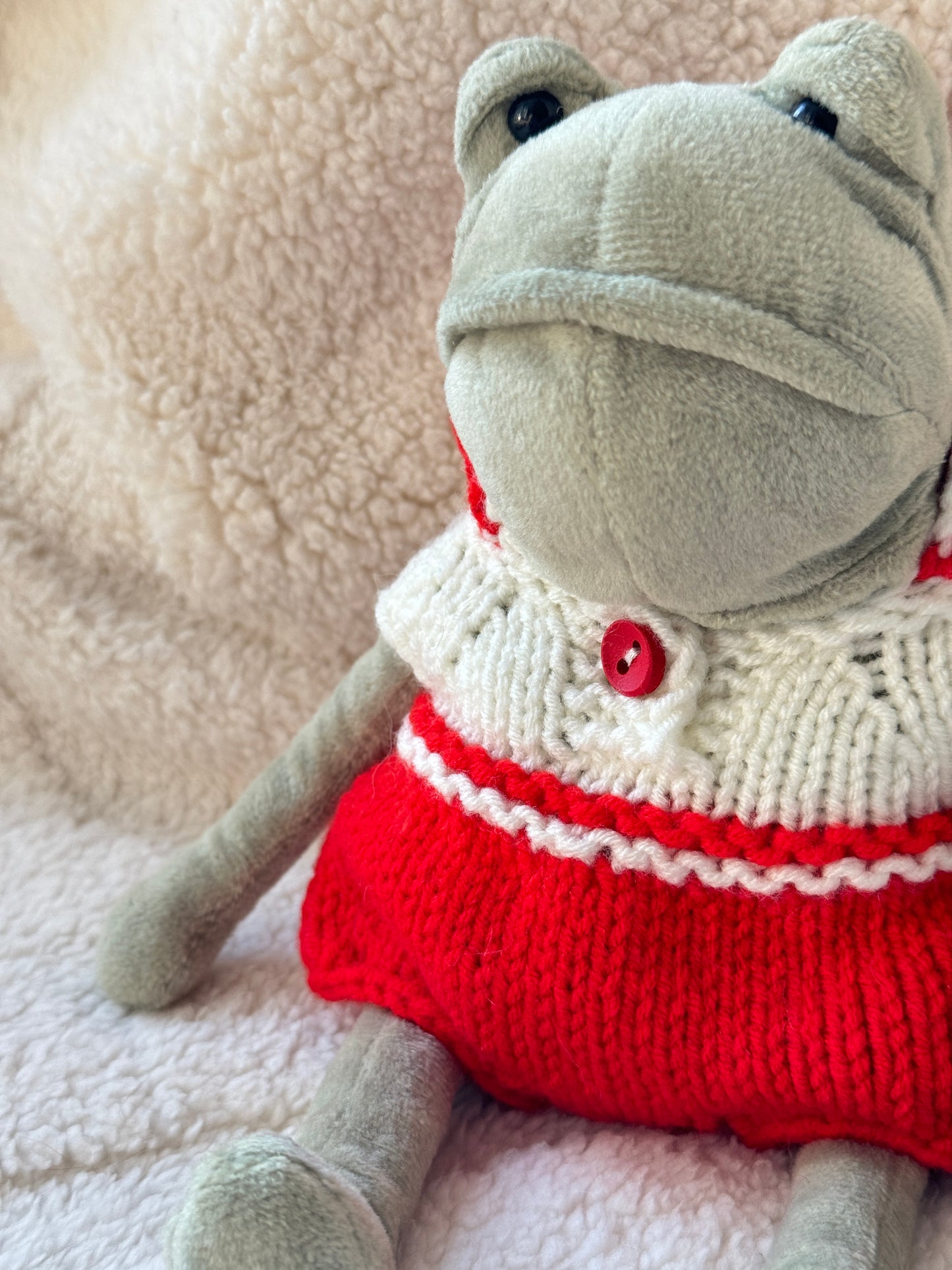 Close-up of cable knit detail and red button on handmade Jellycat frog outfit